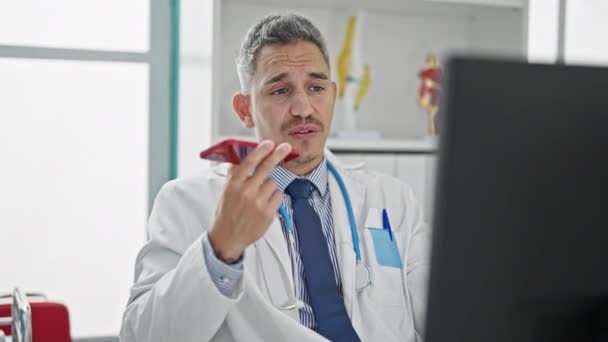 Young Hispanic Man Doctor Sending Voice Message Smartphone Using Computer — Stock Video