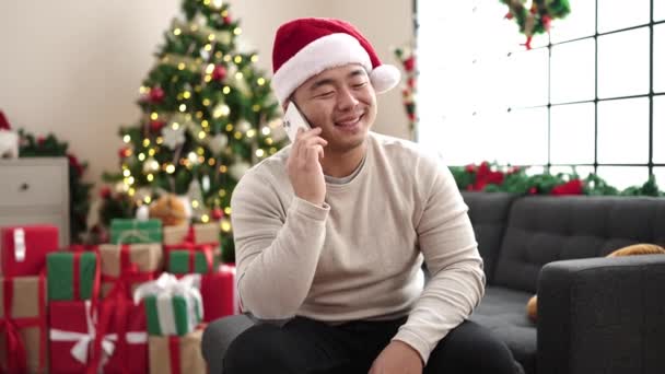 Jovem Chinês Falando Smartphone Sentado Sofá Pela Árvore Natal Casa — Vídeo de Stock