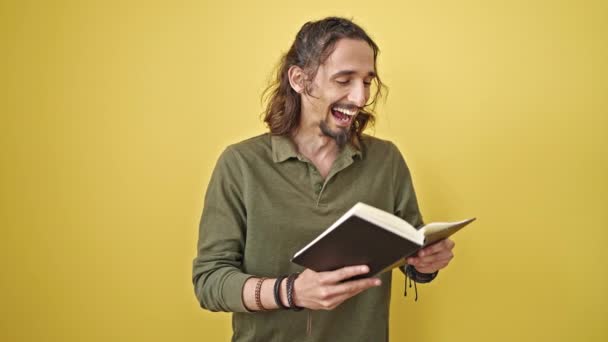 Junger Hispanischer Mann Liest Buch Lächelnd Über Isolierten Gelben Hintergrund — Stockvideo