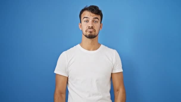 Ung Latinamerikansk Man Står Aningslös Över Isolerad Blå Bakgrund — Stockvideo