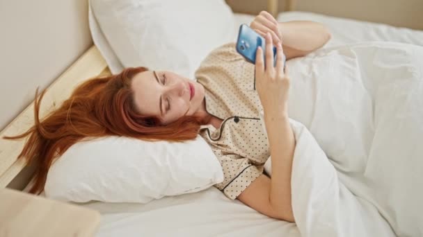 Νεαρή Κοκκινομάλλα Γυναίκα Φινίρισμα Για Χρησιμοποιήσετε Smartphone Ύπνου Στο Υπνοδωμάτιο — Αρχείο Βίντεο