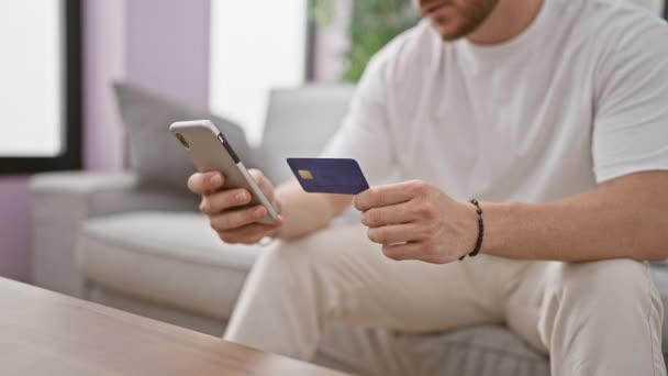 Jovem Hispânico Faz Compras Com Smartphone Cartão Crédito Sentado Sofá — Vídeo de Stock