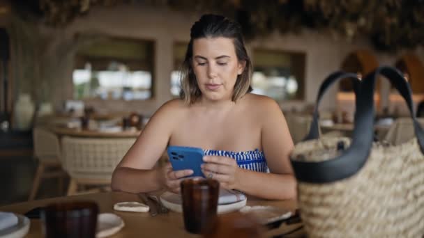Ung Latinamerikansk Kvinna Ler Glad Med Smartphone Sitter Bordet Restaurangen — Stockvideo