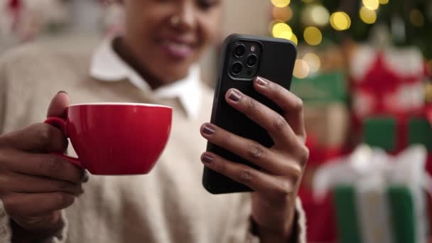 Mujer Afroamericana Usando Teléfono Inteligente Bebiendo Café Sentado Junto Árbol — Vídeo de stock
