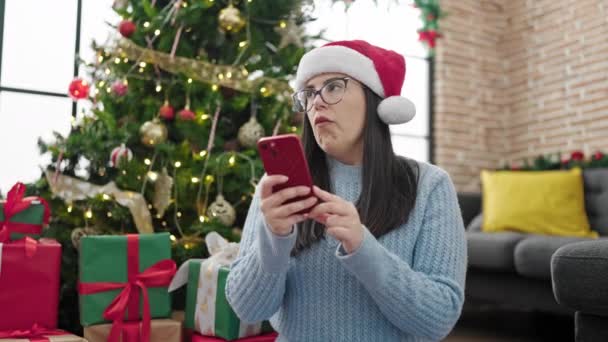 年轻的女人带着圣诞帽 在家里用智能手机打扰到他 — 图库视频影像