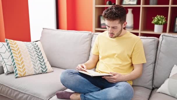 Jovem Hispânico Homem Ler Livro Sentado Sofá Casa — Vídeo de Stock