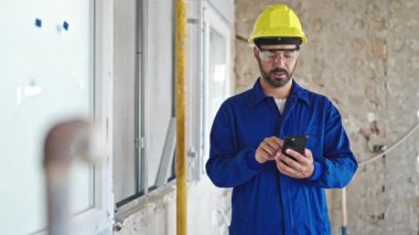 İnşaat alanında akıllı telefon kullanan İspanyol işçi.