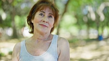 Parkta spor kıyafetleri giyen orta yaşlı bir kadın.