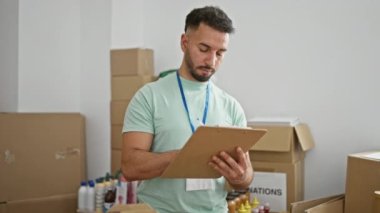 Genç Arap gönüllü yardım merkezinde gülümseyen notlar alıyor.