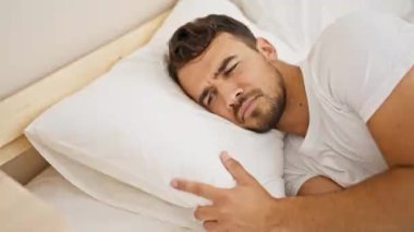 Genç İspanyol adam yatakta uzanıyor ve ağlıyor.