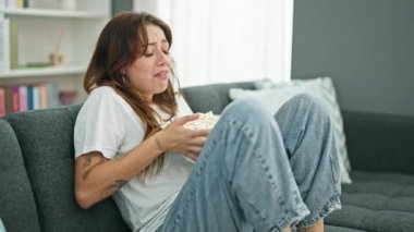 Genç ve güzel İspanyol kadın korku filmi seyrediyor. Evde kanepede oturmuş patlamış mısır yiyor.