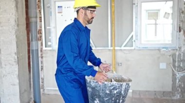 Şantiyede sırtında enkaz olan İspanyol işçi sepeti tutuyor.