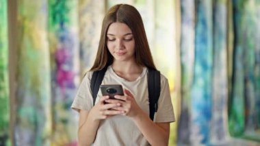Sanat galerisinde akıllı telefon kullanan sırt çantası takan güzel bir kız öğrenci.
