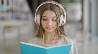 Kütüphanede müzik dinleyen güzel bir kız öğrenci.