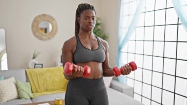 African american woman using dumbbells training at home