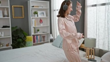 Genç kadın yatak odasında müzik dinliyor.