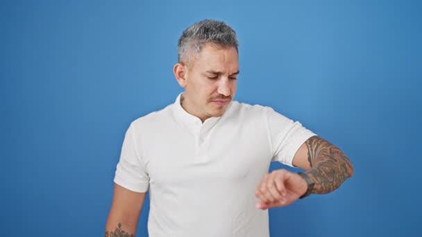 Jeune Homme Hispanique Regardant Montre Stressée Sur Fond Bleu Isolé — Video