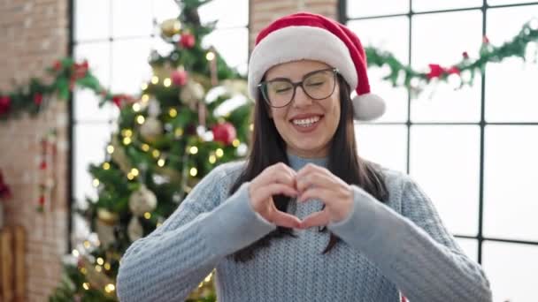年轻的惊慌失措的女人在家里的圣诞树旁做着心动的动作 — 图库视频影像