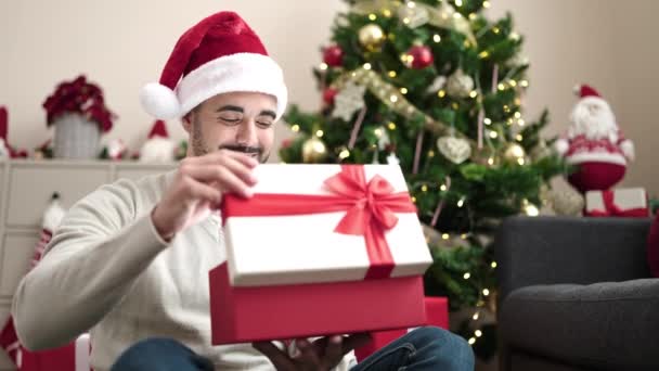 Jovem Hispânico Desempacotando Presente Sentado Árvore Natal Casa — Vídeo de Stock