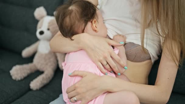 自宅でソファー授乳中の赤ちゃんに座っている母と娘 — ストック動画