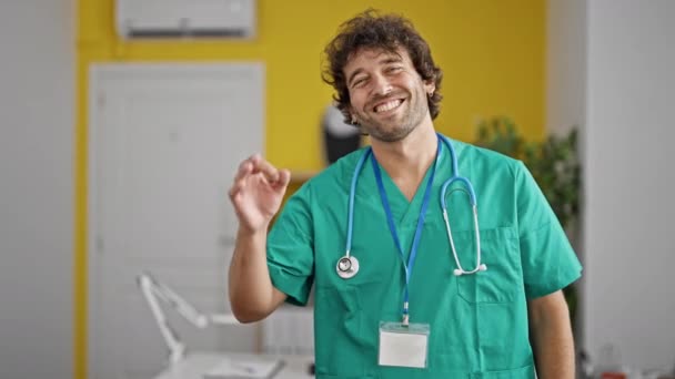 年轻的惊慌失措的医生在诊所里做着一个微笑的姿势 — 图库视频影像