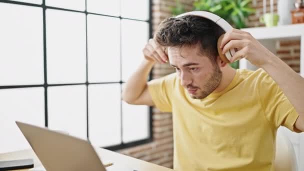 Νεαρός Ισπανός Που Χρησιμοποιεί Φορητό Υπολογιστή Και Ακουστικά Καθισμένος Στο — Αρχείο Βίντεο