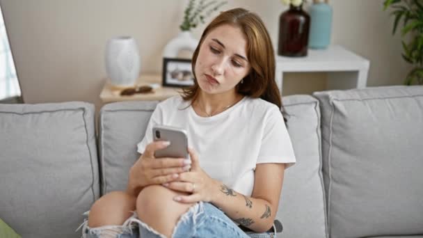 Jovem Mulher Usando Smartphone Sentado Sofá Olhando Chateado Casa — Vídeo de Stock