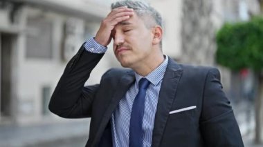Latin kökenli genç bir iş adamı sokakta stres altında.