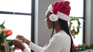 Afrikalı Amerikalı bir kadın Noel ağacını evde süslüyor.