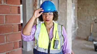 İnşaat alanında yüzü ciddi bir şekilde duran genç, güzel Latin kadın müteahhit.