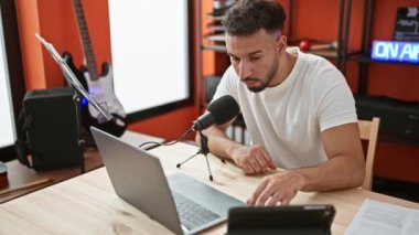 Genç Arap adam müzik muhabiri radyo programı stüdyosunda konuşuyor.