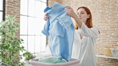 Genç kızıl saçlı, gülümseyen, kendine güveni tam çamaşırhanede çamaşır ipine asılı duran bir kadın.