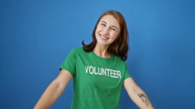 Genç bayan gönüllü, mavi arka planda kutlama yaparken kameraya işaret ediyor.