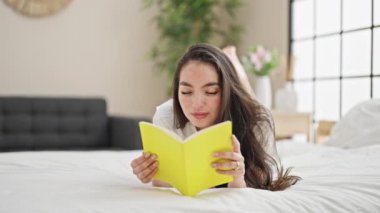 Genç, güzel, İspanyol bir kadın yatak odasında kitap okuyor.