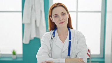 Genç kızıl saçlı kadın doktor klinikte gülümsüyor.