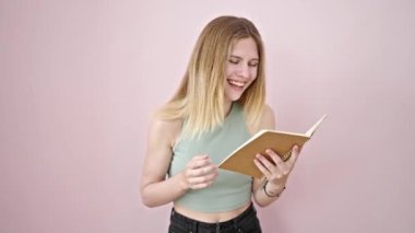 Genç sarışın kadın kitap okuyor, pembe arka planda gülüp duruyor.