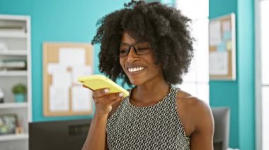 Afrika kökenli Amerikalı iş kadını ofiste çalışan akıllı telefonuyla sesli mesaj gönderiyor.