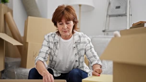中年妇女打开包装纸板箱厌倦了新家 — 图库视频影像