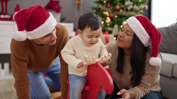自宅でクリスマスツリーでロッキングトナカイと遊ぶカップルと息子 — ストック動画