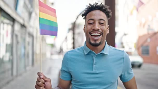 Hombre Afroamericano Sonriendo Confiado Sosteniendo Bandera Arco Iris Calle — Vídeo de stock