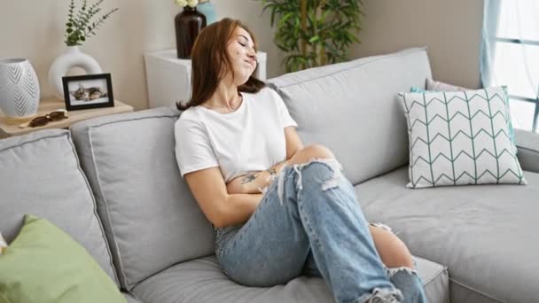 自宅でソファーに座っている胃痛のために苦しんでいる若い女性 — ストック動画