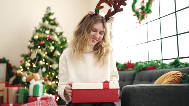 Joven Mujer Rubia Desembalaje Regalo Sentado Sofá Por Árbol Navidad — Vídeos de Stock