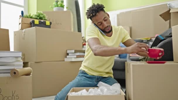 African American Man Unpacking Cardboard Box Talking Smartphone New Home — Stock Video