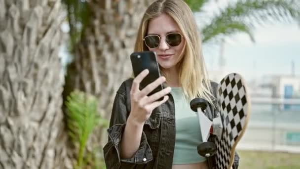 Ung Blond Kvinna Som Håller Skridsko Med Hjälp Smartphone Parken — Stockvideo