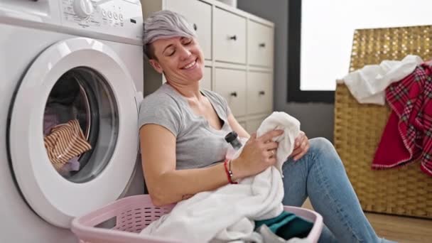 洗濯室で洗濯機の洗濯機に自信を持って笑っている若い女性 — ストック動画