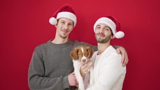 Two Men Couple Wearing Christmas Hat Hugging Dog Isolated Red — Stock Video