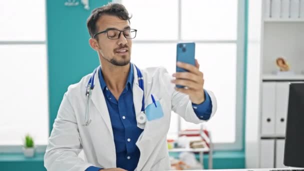 Jovem Hispânico Homem Médico Fazendo Videochamada Com Smartphone Clínica — Vídeo de Stock