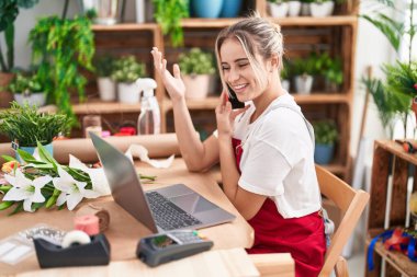 Çiçekçide bilgisayarla konuşan sarışın bir çiçekçi.