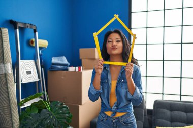 Genç Asyalı bir kadın yeni evine taşınıyor ve kameraya bakıyor. Öpücük savuruyor, sevimli ve seksi. aşk ifadesi. 