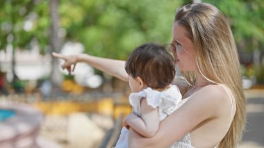 Anne ve kızı parkta birbirlerine gülümsüyorlar.